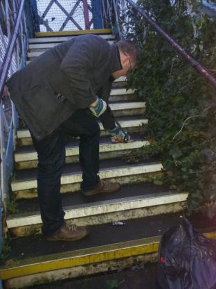 Lib Dem Anthony Fairclough collecting litter from the footbridge